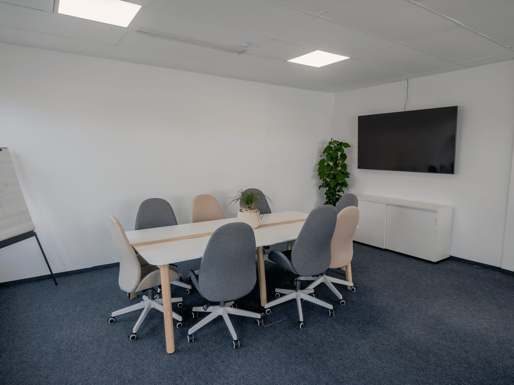 Meeting room with a long table, a wall-mounted screen and a flipchart